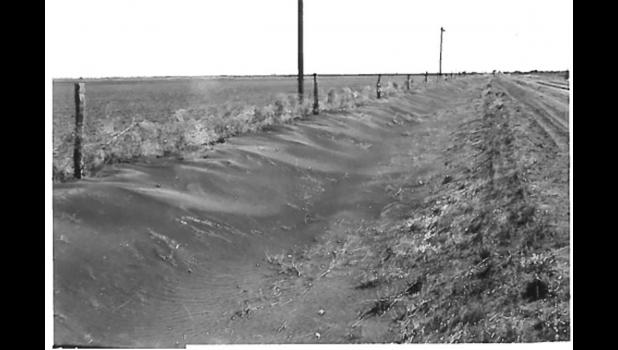 Milesville, 4/3/61, day after six hour 50 mph NW wind. Top soil piled up 3 feet in fence and in road ditch. Courtest Photo