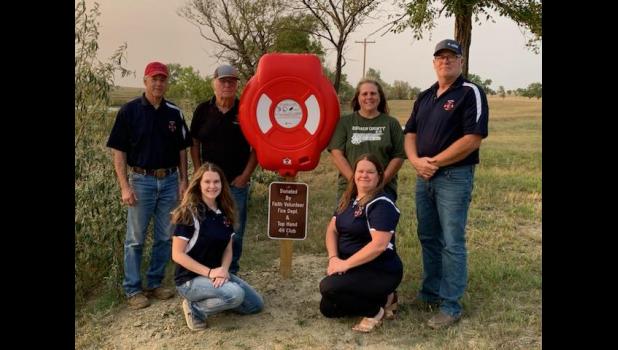 Faith Volunteer Fire Department ... pictured with Top Hand 4-H Advisor Kim Bachman at Durkee Lake, next to the donated life preserver. Back row: Chief Fred Hulm, Mayor Glen Haines, 4-H Advisor Kim Bachman, and Justin Haines. Front row: Lenae Hulm and Shara Haines. Photo Courtesy Kris Escott