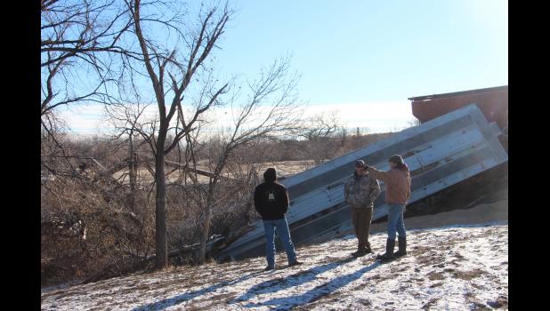 Nels Crowser (right) visits others as they try and figure out the best way to get to the grain and get it trucked away from the accident.