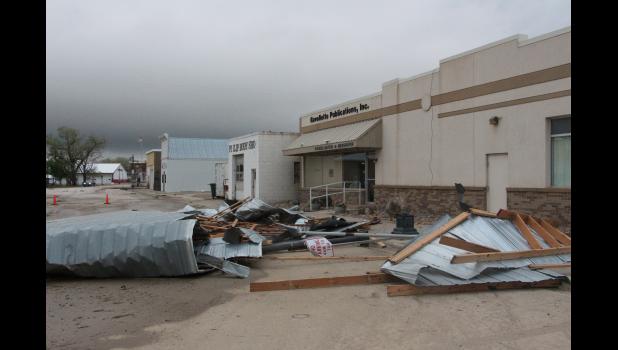The storm on Sunday night caused more structural damage as the roof of the Philip Body Shop was lifted off and blown onto the top of the Ravellette Publications building. Some of the tin and 2 x 10 frame boards stayed on top of the newspaper office, with the remainder landing in the street on the corner of E Oak Street and S Wood Ave.