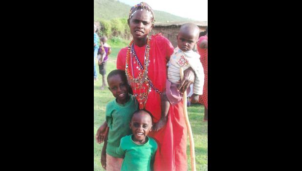 A young Maasai woman poses with her three children. Her husband would be considered well on his way to wealth, since wealth for the Maasai is measured in cattle and children.