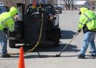 Here Matt Reckling places the hot rubber product into the freshly cleaned cracks along East Oak street Sunday morning, while Robbie Shipp levels and make sure cracks are completely filled before the product cools and firms up.